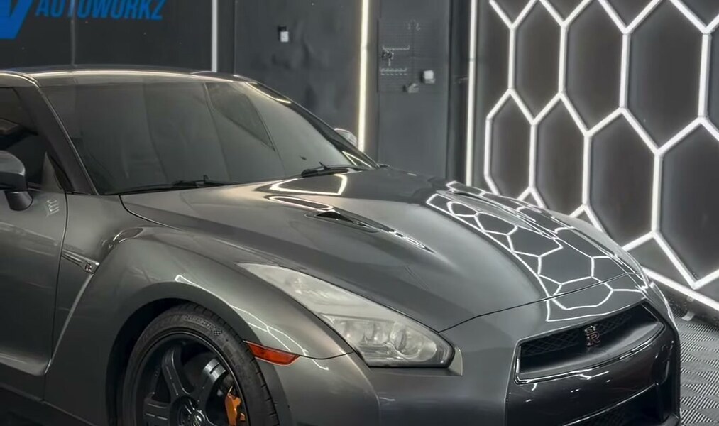 Inside the LV Autoworkz hexagon-lit studio, a GT-R under the LED honeycomb wall
